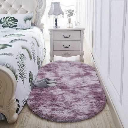 Alfombra ovalada shaggy rosa para pie de cama.
